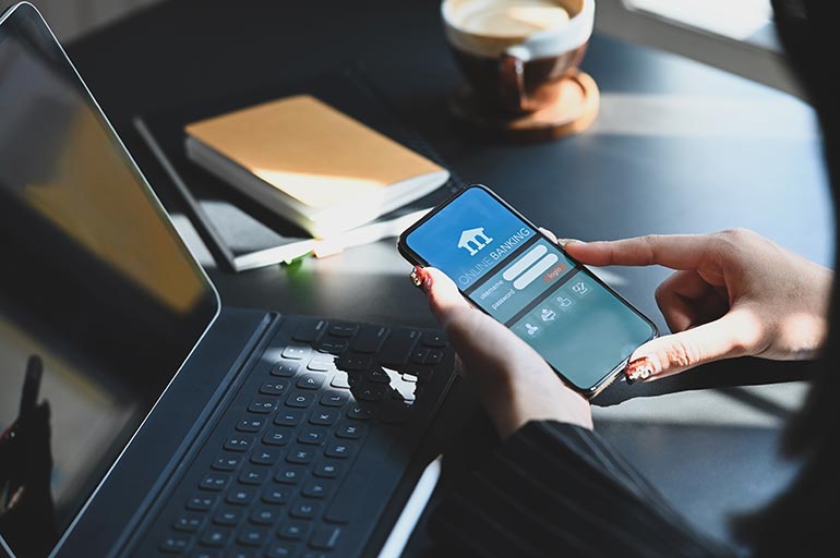 woman holding smartphone in hands while doing online financial transaction